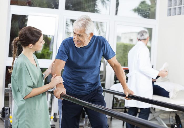 caregiver helping older man at physical therapy appointment