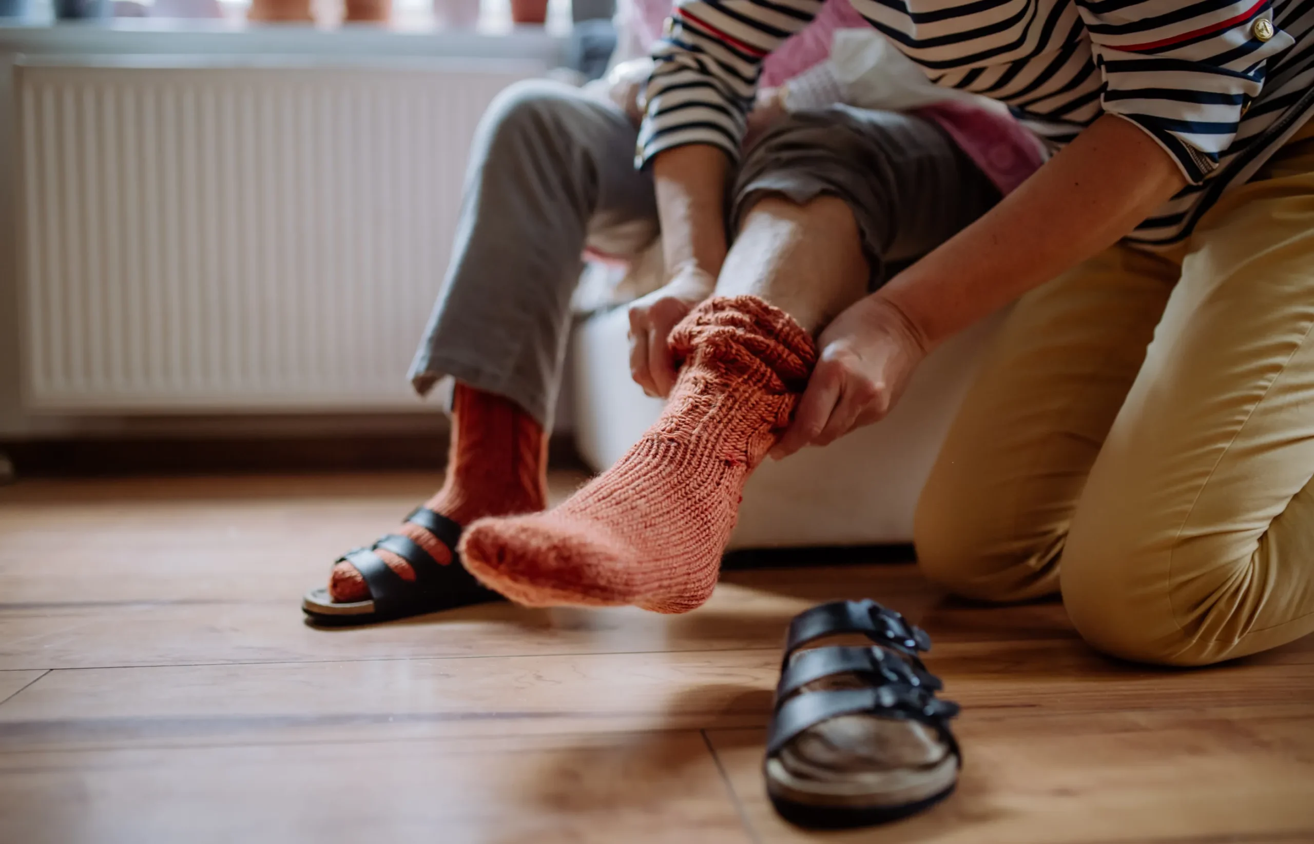 senior living caregiver helping elderly woman put socks on her feet