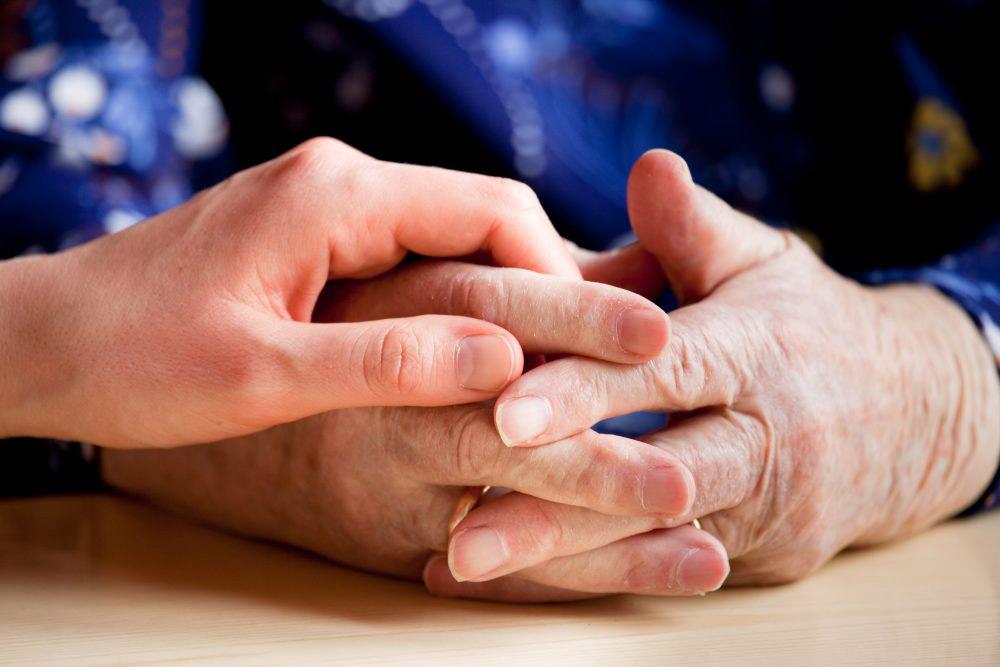 a young person holding the hands of and older person