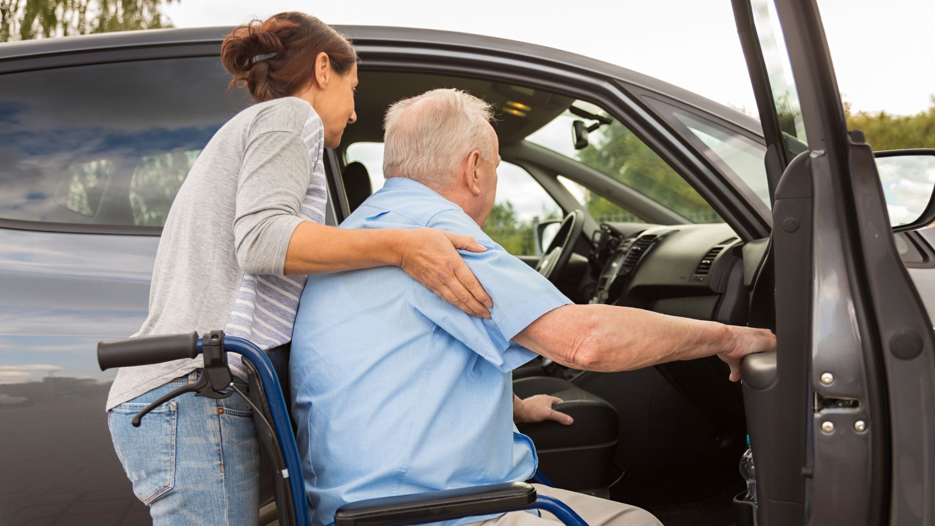Caregiving Is A Career For Everyone: women carrying man in wheelchair into car