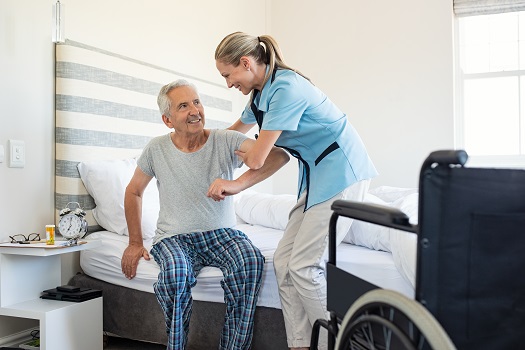 find a good caregiver - female caregiver helping elderly man out of bed