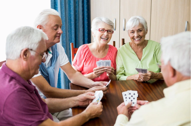 Group of elderly sitting at a table playing cards together
