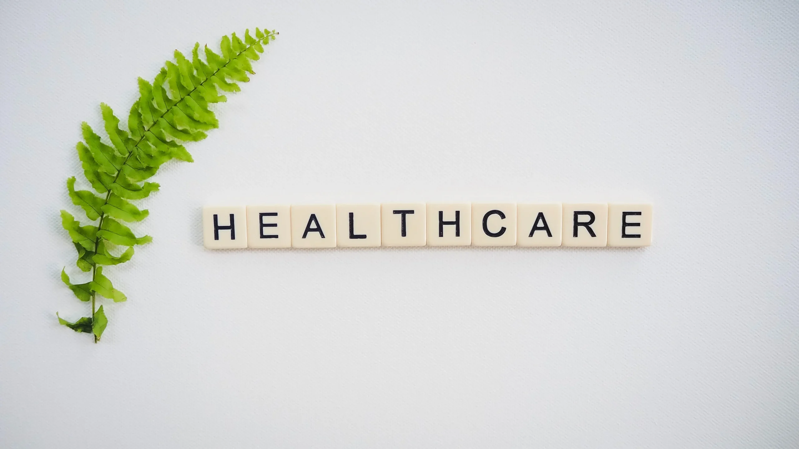 Scrabble letters spelling out healthcare with a leaf on a white background