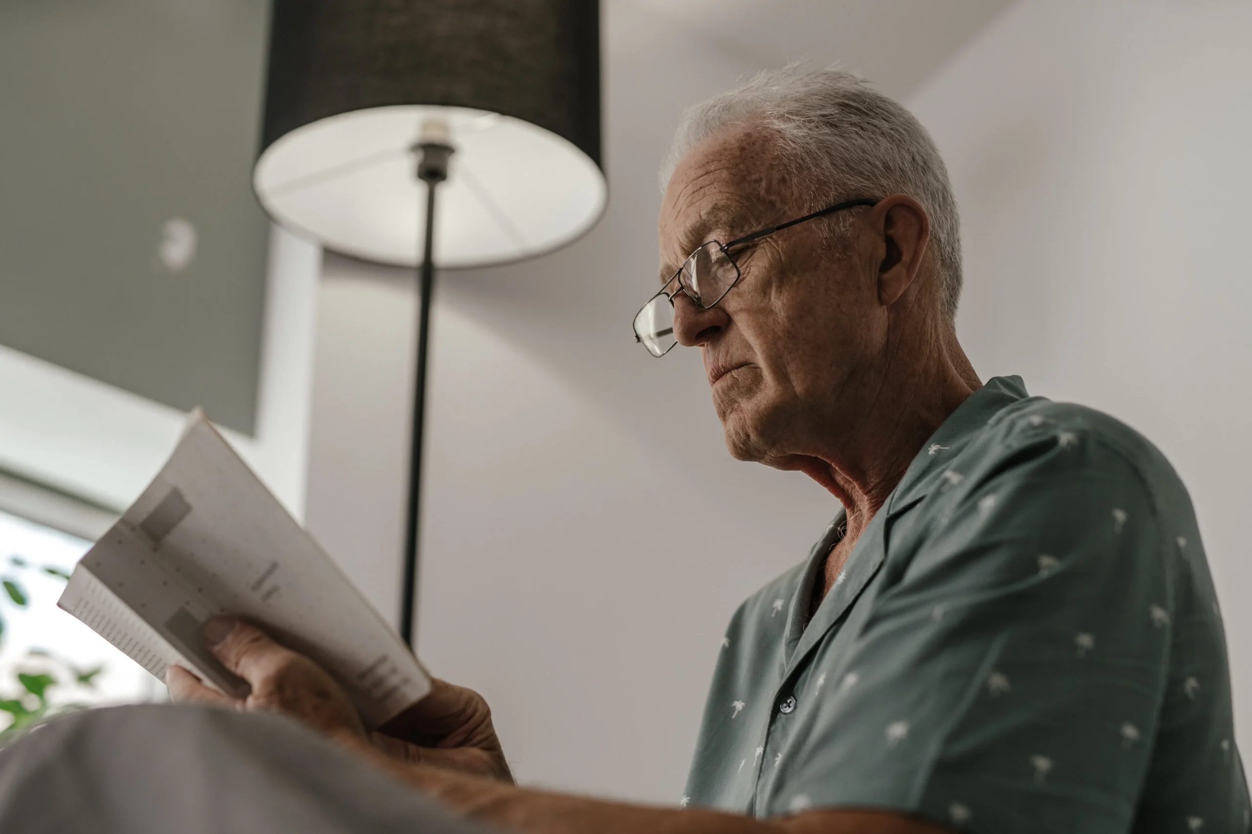 Elderly man looking at book in house
