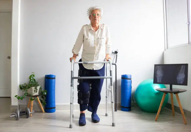knee replacement recovery at home, elderly woman using a walker after knee surgery