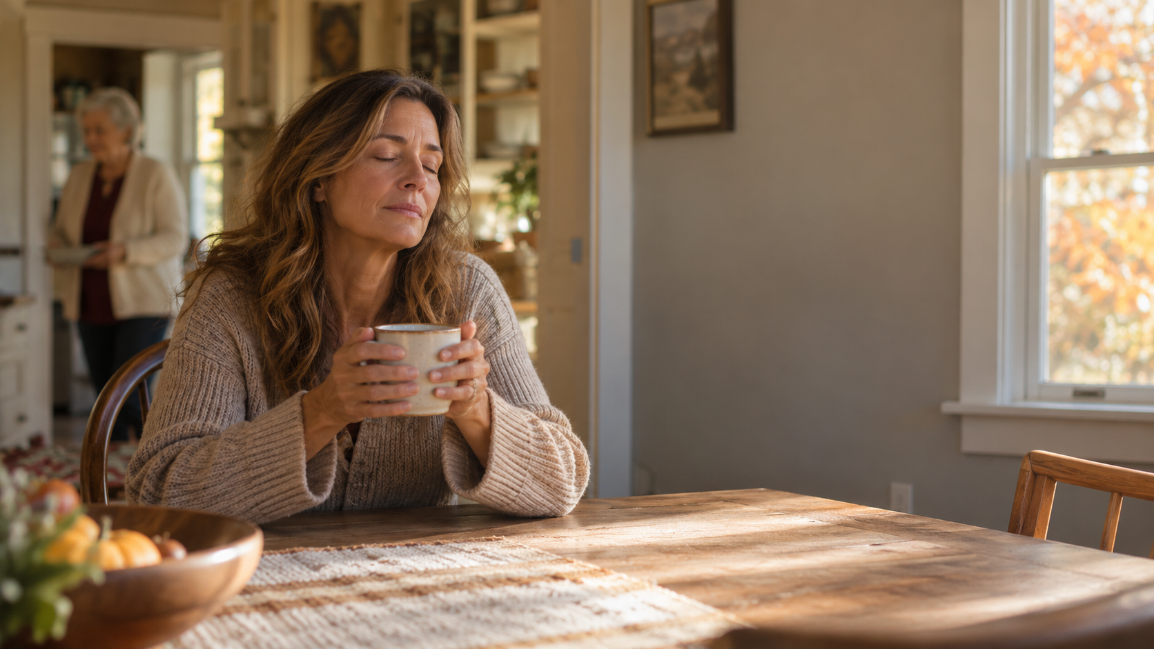 Adult daughter sitting at a kitchen table with her eyes closed while caring for her elderly mother